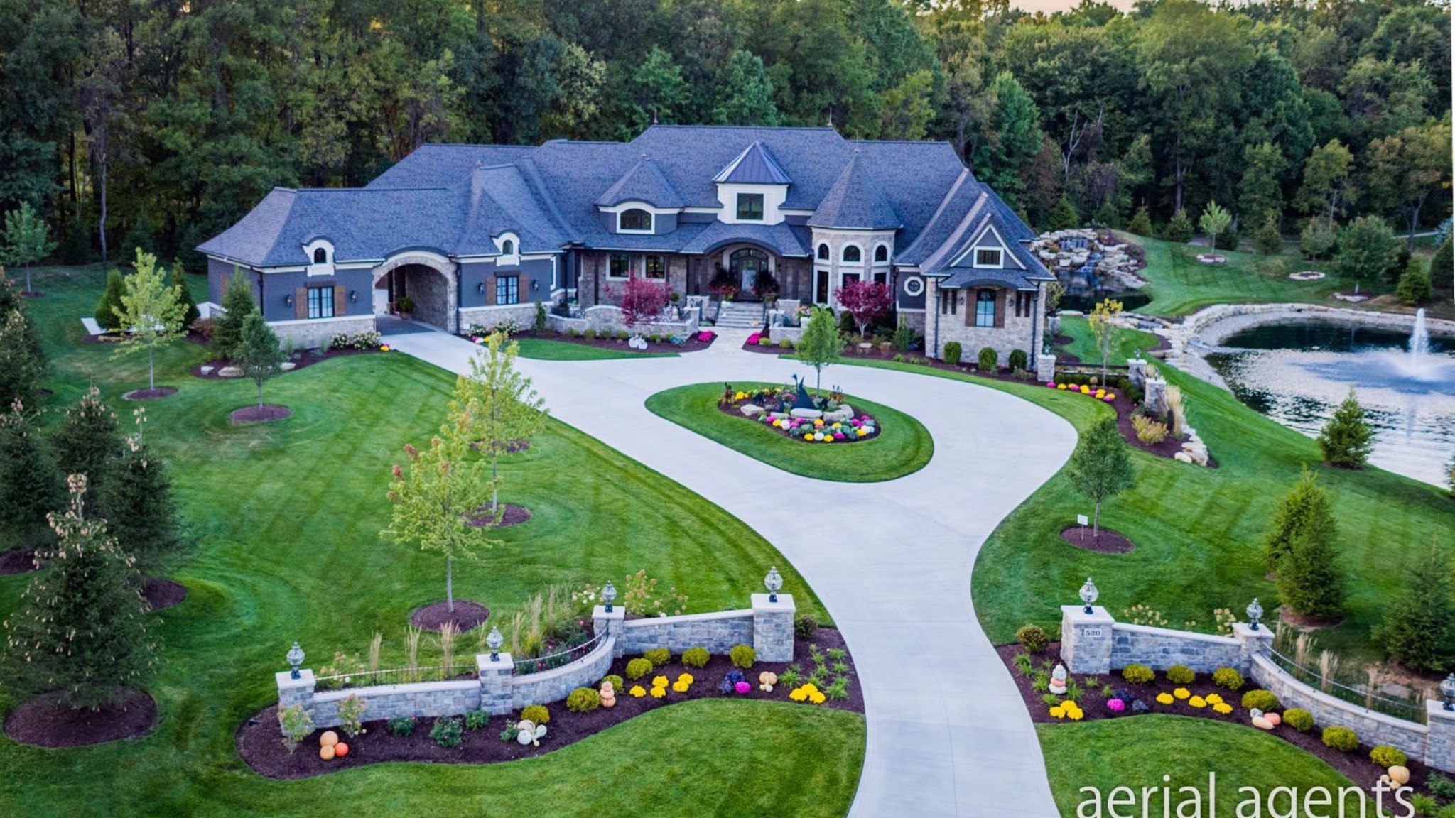 Aerial view of a custom home with circular drive and landscaped grounds